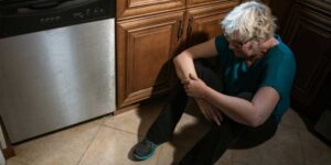 Mulher De Camisa Verde E Calça Preta Sentada No Balcão Da Cozinha
